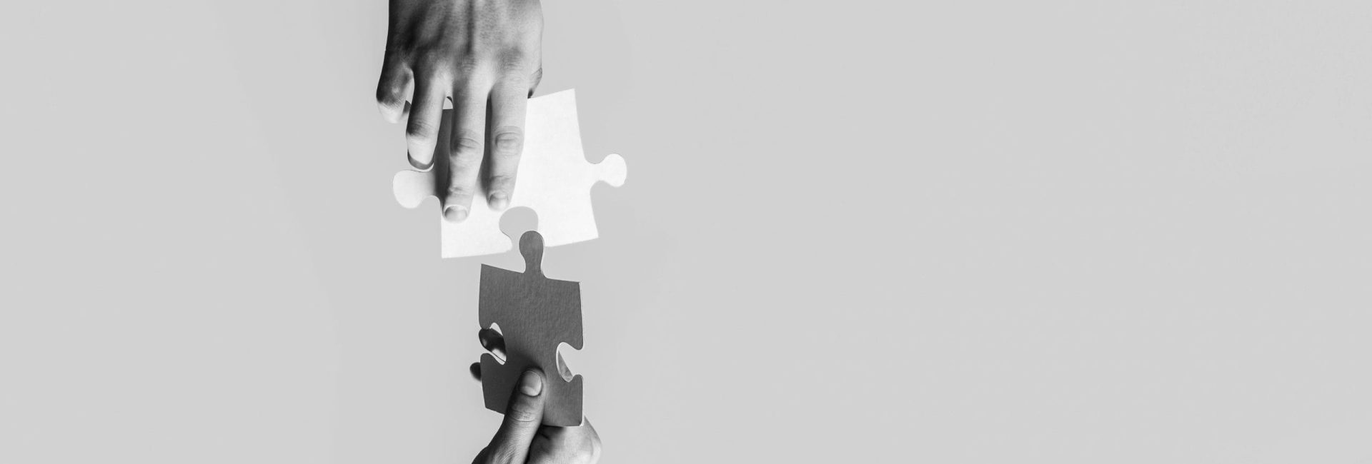 Closeup hands of man connecting jigsaw puzzle. Business solutions, success and strategy concept. Black and white. Two hands trying to connect couple puzzle with yellow background